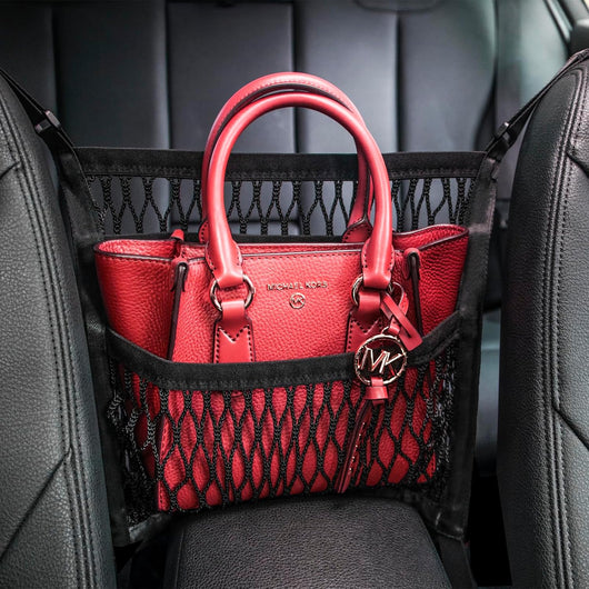 Car seat organizer with dog barrier mesh and storage pockets installed between front seats to organize essentials and keep pets safely in the back seat.